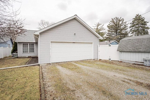 garage with a storage unit, dirt driveway, and fence