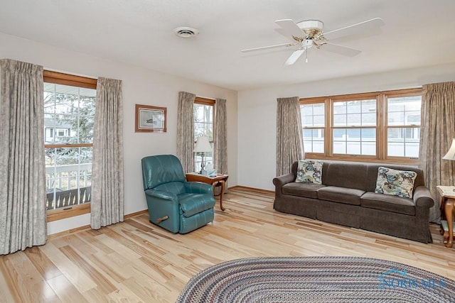 living area featuring ceiling fan, visible vents, baseboards, and wood finished floors