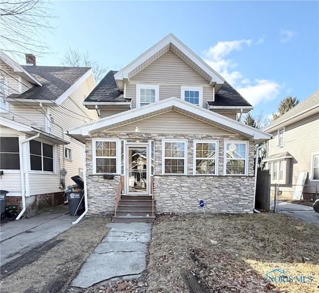 view of front of house featuring stone siding and fence