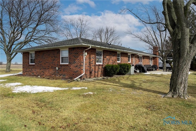 view of home's exterior featuring brick siding, crawl space, a chimney, and a lawn