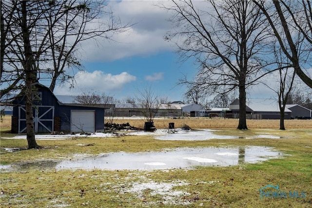 view of yard featuring a garage, an outbuilding, fence, and a barn