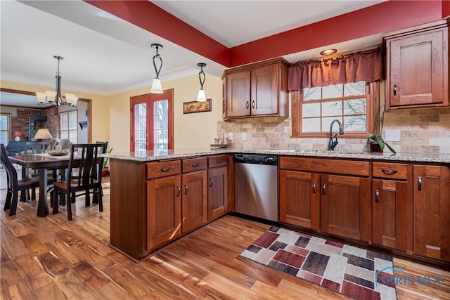 kitchen featuring a sink, a peninsula, stainless steel dishwasher, and wood finished floors