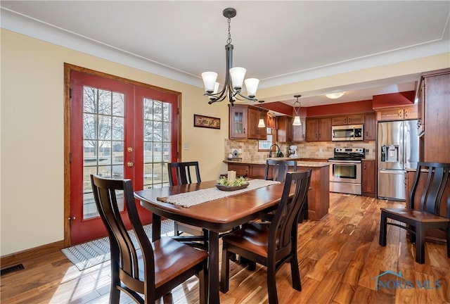 dining space featuring a notable chandelier, french doors, visible vents, and light wood-style floors