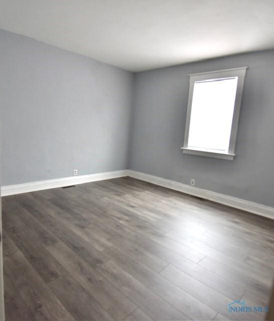 empty room with dark wood-style flooring and baseboards