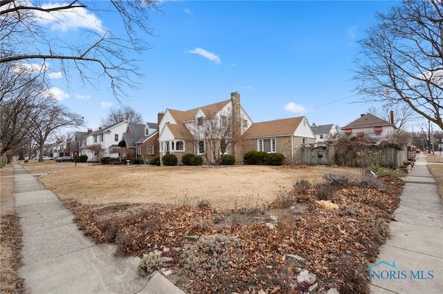 view of front of home featuring a residential view, fence, and a chimney