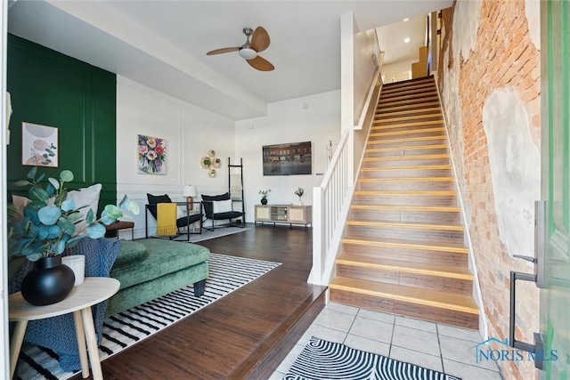 stairs featuring a ceiling fan, a decorative wall, and tile patterned floors