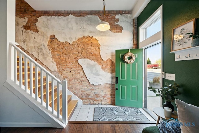 foyer featuring brick wall, stairs, and wood finished floors