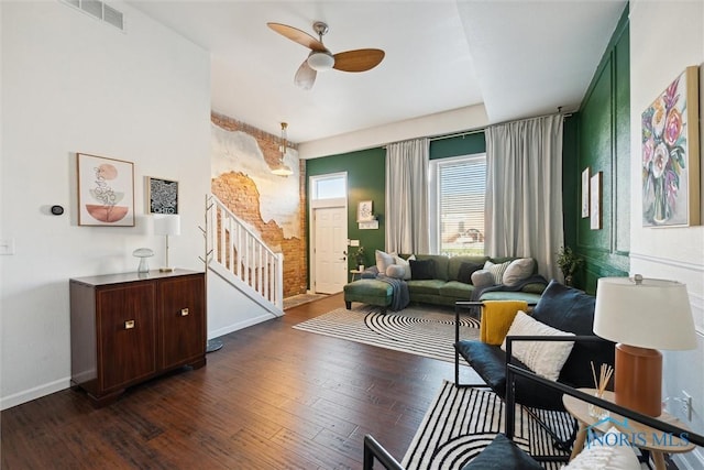 interior space featuring dark wood finished floors, visible vents, stairway, a ceiling fan, and baseboards