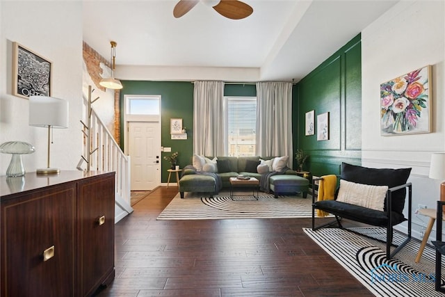 living area with ceiling fan, stairway, and dark wood-style flooring