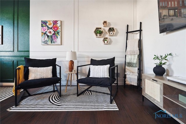 living area with dark wood finished floors and a decorative wall