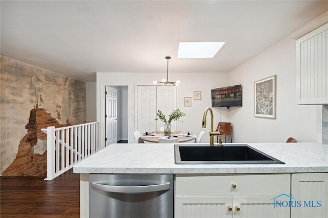 kitchen with dark wood finished floors, white cabinets, light countertops, stainless steel dishwasher, and a sink