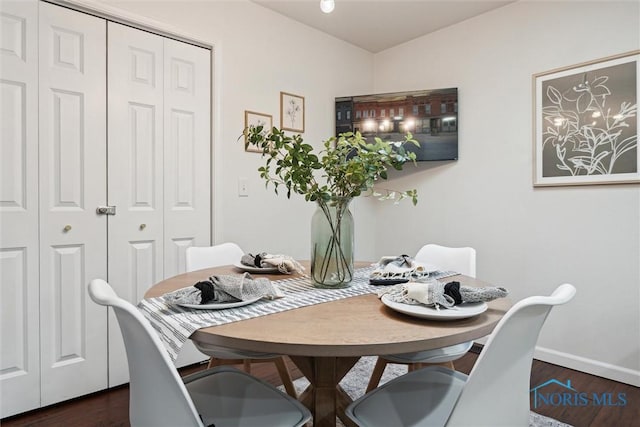 dining space featuring dark wood-type flooring and baseboards