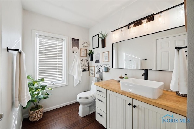 bathroom featuring toilet, baseboards, wood finished floors, and vanity