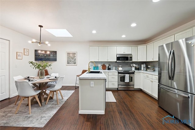 kitchen with tasteful backsplash, appliances with stainless steel finishes, dark wood-style flooring, light countertops, and a sink