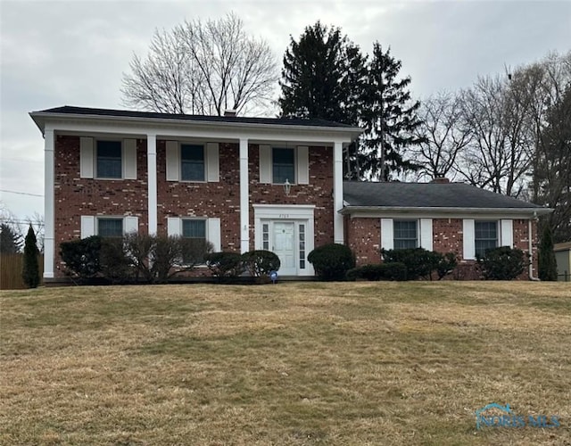 greek revival house with a front lawn and brick siding