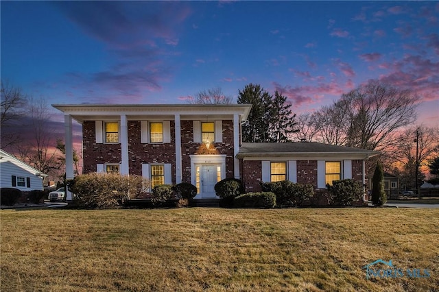 neoclassical / greek revival house featuring brick siding and a yard