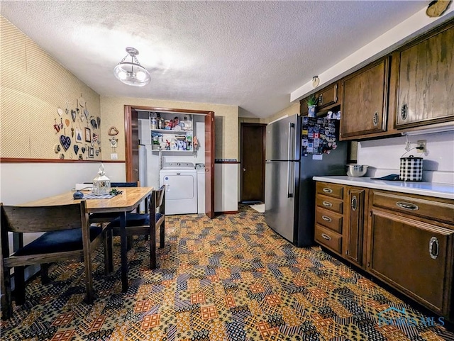 kitchen featuring freestanding refrigerator, light countertops, dark brown cabinets, a textured ceiling, and separate washer and dryer