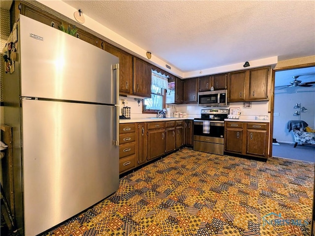 kitchen featuring a sink, stainless steel appliances, dark brown cabinets, and light countertops