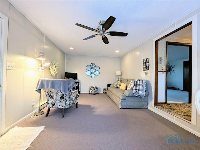 living room with a ceiling fan, a decorative wall, and carpet flooring