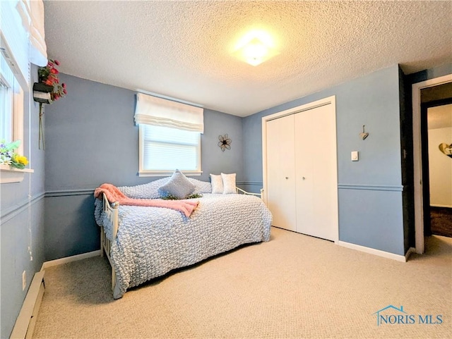 carpeted bedroom featuring a textured ceiling, baseboard heating, a closet, and baseboards