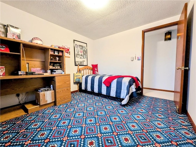 bedroom with baseboards, dark carpet, and a textured ceiling