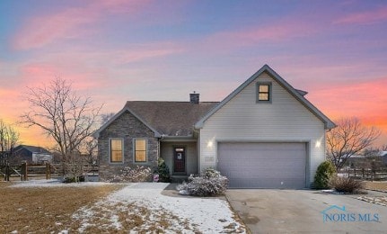 view of front of home with driveway, stone siding, a chimney, and an attached garage