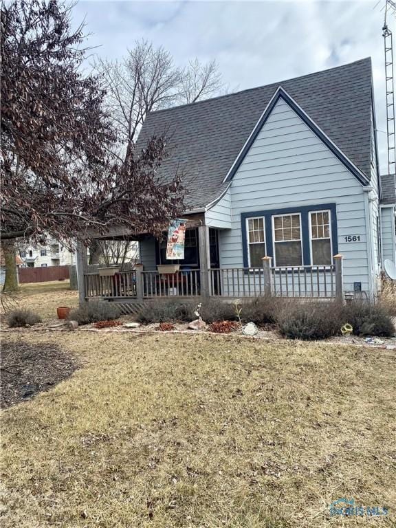 view of front of house featuring covered porch, a shingled roof, and a front lawn