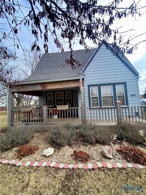 rear view of property featuring a porch and roof with shingles