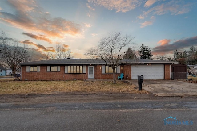 ranch-style house with a garage, concrete driveway, and brick siding