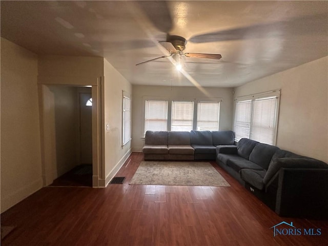 living area featuring visible vents, dark wood finished floors, baseboards, and ceiling fan