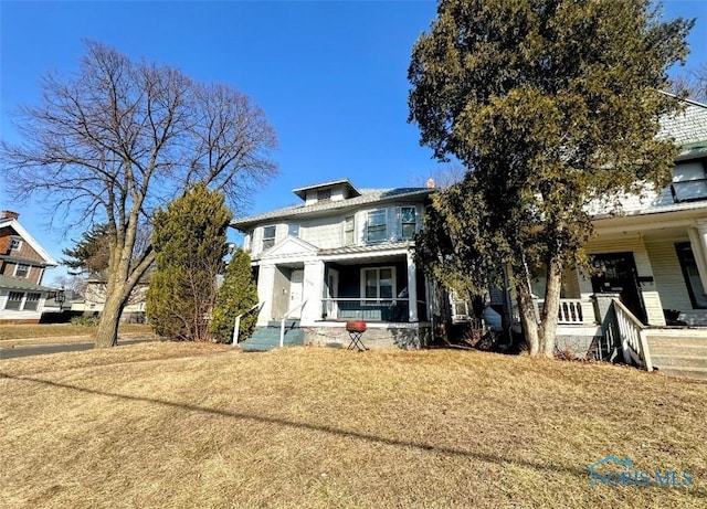 american foursquare style home featuring a porch and a front lawn