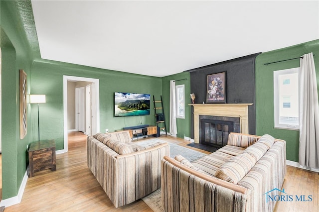 living room featuring a fireplace, wood finished floors, and baseboards