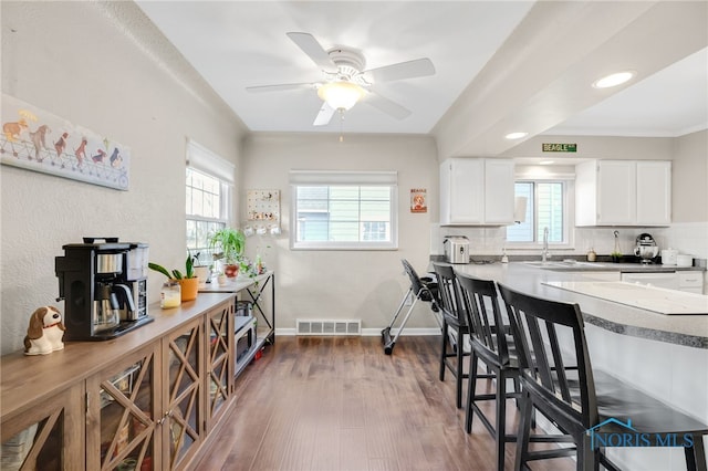 kitchen featuring visible vents, decorative backsplash, dark wood-type flooring, white cabinetry, and baseboards