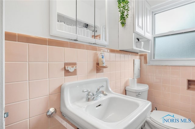 full bathroom with a sink, tile walls, and toilet