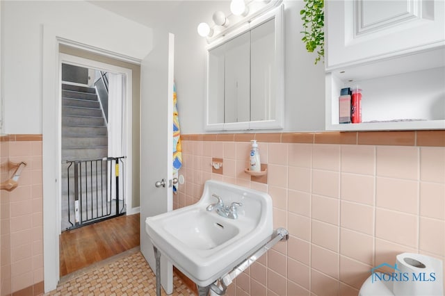 bathroom featuring wainscoting, a sink, tile walls, and tile patterned floors