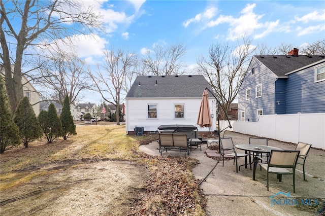 rear view of property with roof with shingles, a hot tub, central AC unit, a patio area, and fence