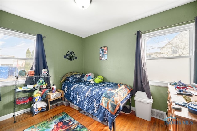 bedroom featuring wood finished floors, visible vents, and baseboards