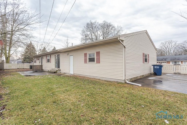 rear view of house featuring entry steps, a yard, fence, and a patio