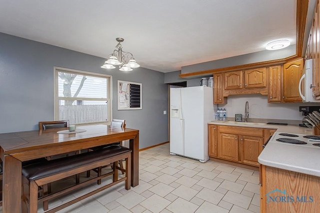 kitchen featuring decorative light fixtures, a notable chandelier, light countertops, a sink, and white appliances