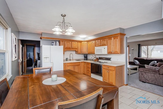 kitchen with a chandelier, white appliances, open floor plan, light countertops, and hanging light fixtures