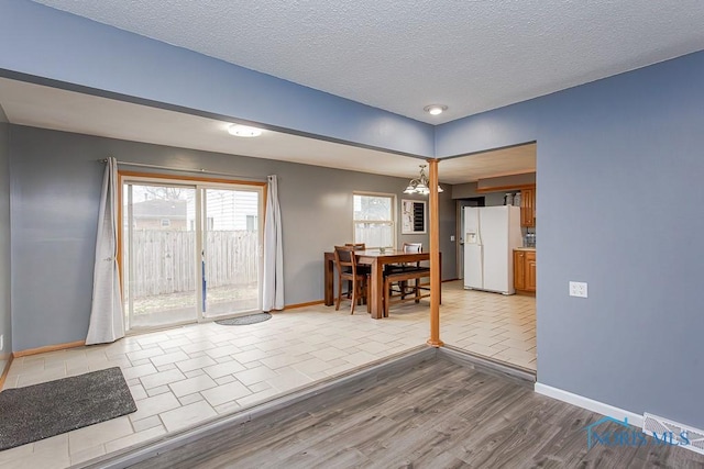 dining space with a textured ceiling, wood finished floors, and baseboards