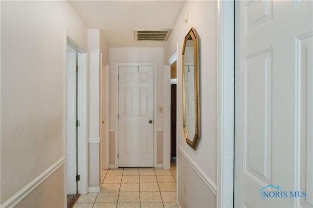 hall featuring visible vents and light tile patterned floors