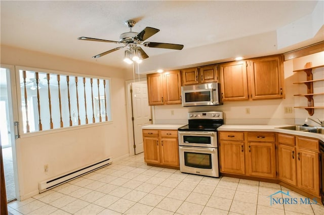 kitchen featuring ceiling fan, appliances with stainless steel finishes, light countertops, a baseboard heating unit, and a sink