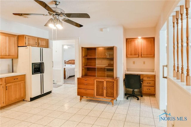 kitchen with light countertops, white refrigerator with ice dispenser, built in study area, and a ceiling fan