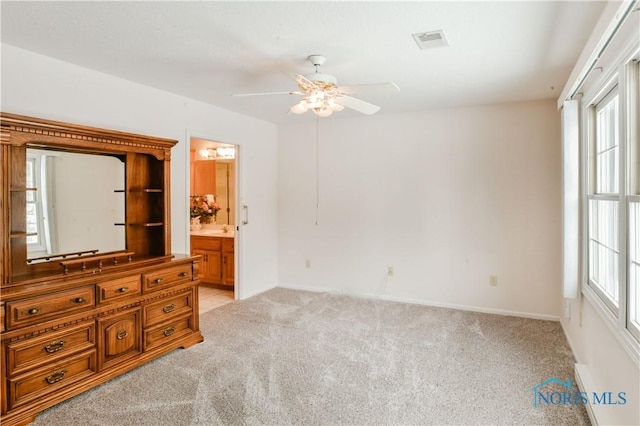 bedroom featuring visible vents, connected bathroom, light carpet, and baseboards