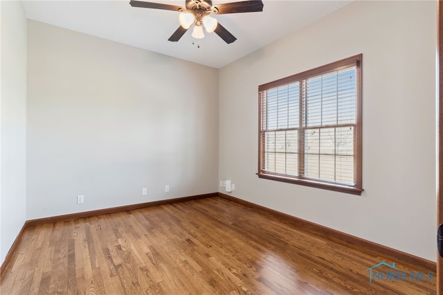 empty room featuring wood finished floors, a ceiling fan, and baseboards