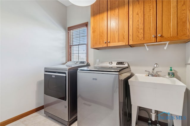 washroom with washer and clothes dryer, a sink, cabinet space, and baseboards