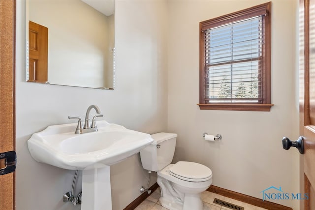 half bath featuring baseboards, visible vents, toilet, and tile patterned floors