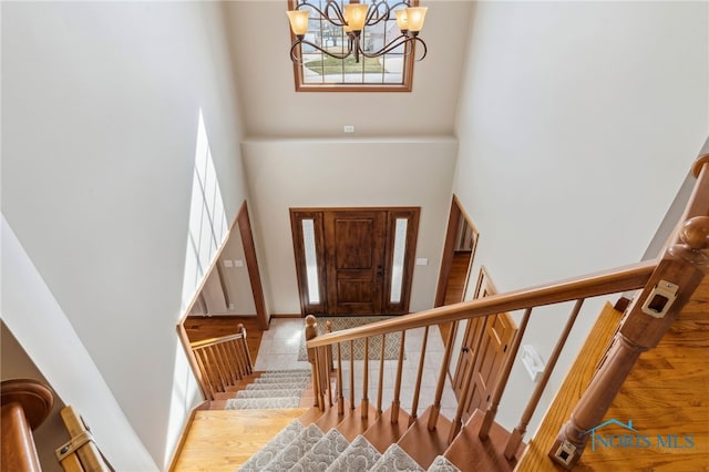 entrance foyer featuring a chandelier, stairway, a towering ceiling, and baseboards