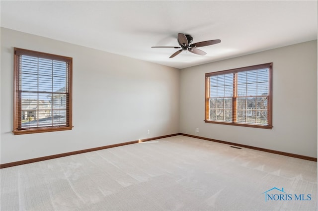 carpeted empty room with a ceiling fan, visible vents, and baseboards